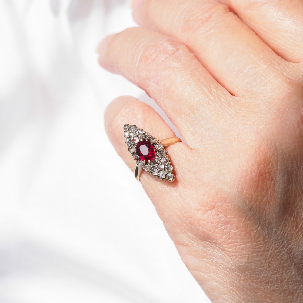 An antique late-nineteenth-century French 18k gold navette cluster ring featuring a central oval red ruby surrounded by multiple rose-cut diamonds. View XVII