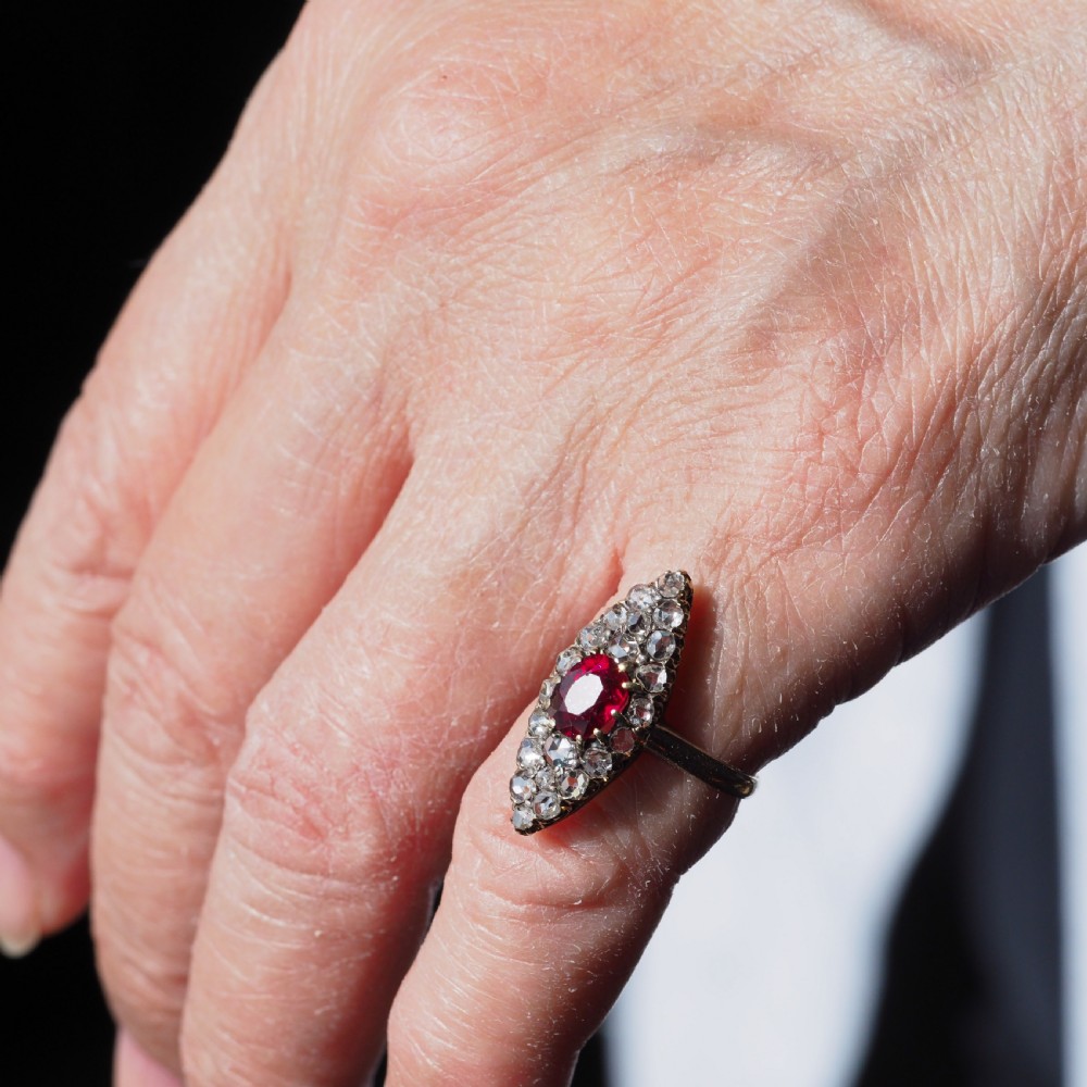 An antique late-nineteenth-century French 18k gold navette cluster ring featuring a central oval red ruby surrounded by multiple rose-cut diamonds. View XVIII