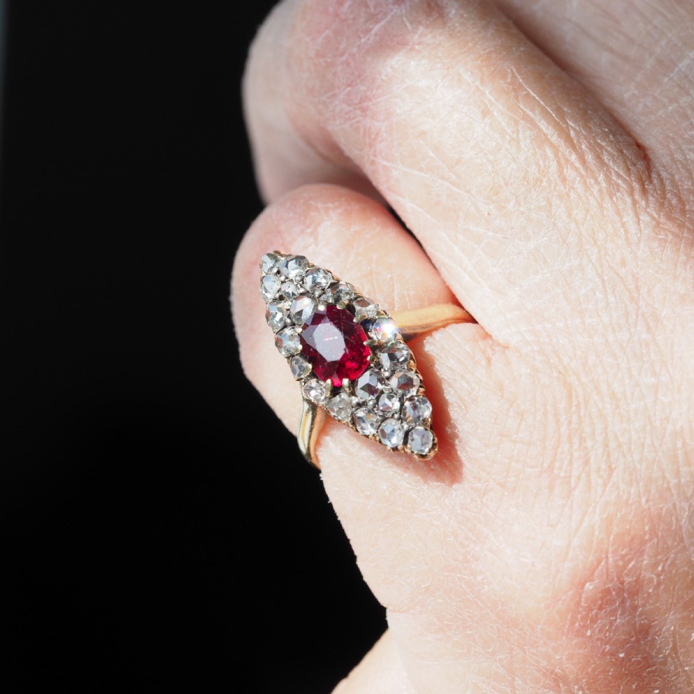 An antique late-nineteenth-century French 18k gold navette cluster ring featuring a central oval red ruby surrounded by multiple rose-cut diamonds. View XIX
