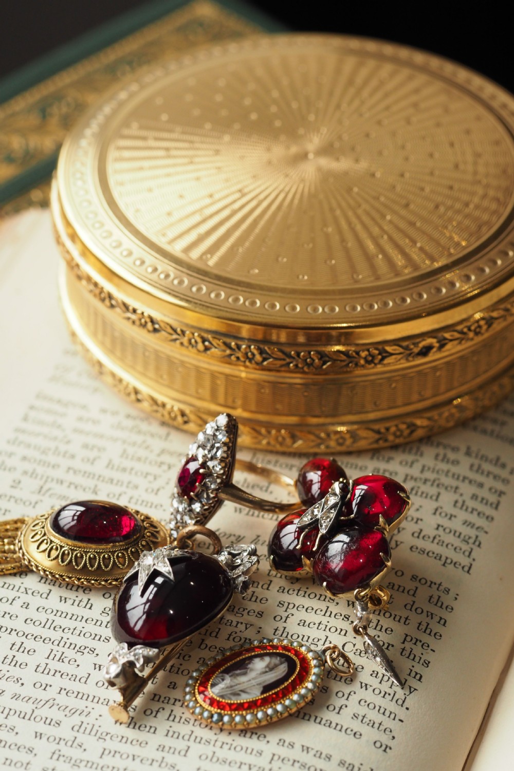 A Victorian 15ct gold oval Etruscan Revival pendant set with a central cabochon garnet and decorated with fine wirework and hanging spike tassels. View XIX