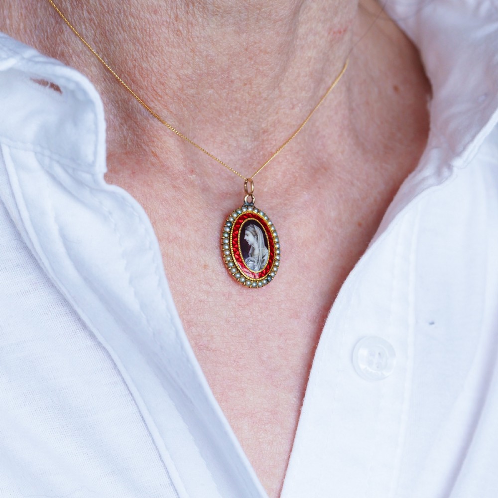An oval Georgian gold pendant featuring a sepia miniature profile portrait surrounded by a red enamel border and a frame of seed pearls on a fine gold chain. View IX