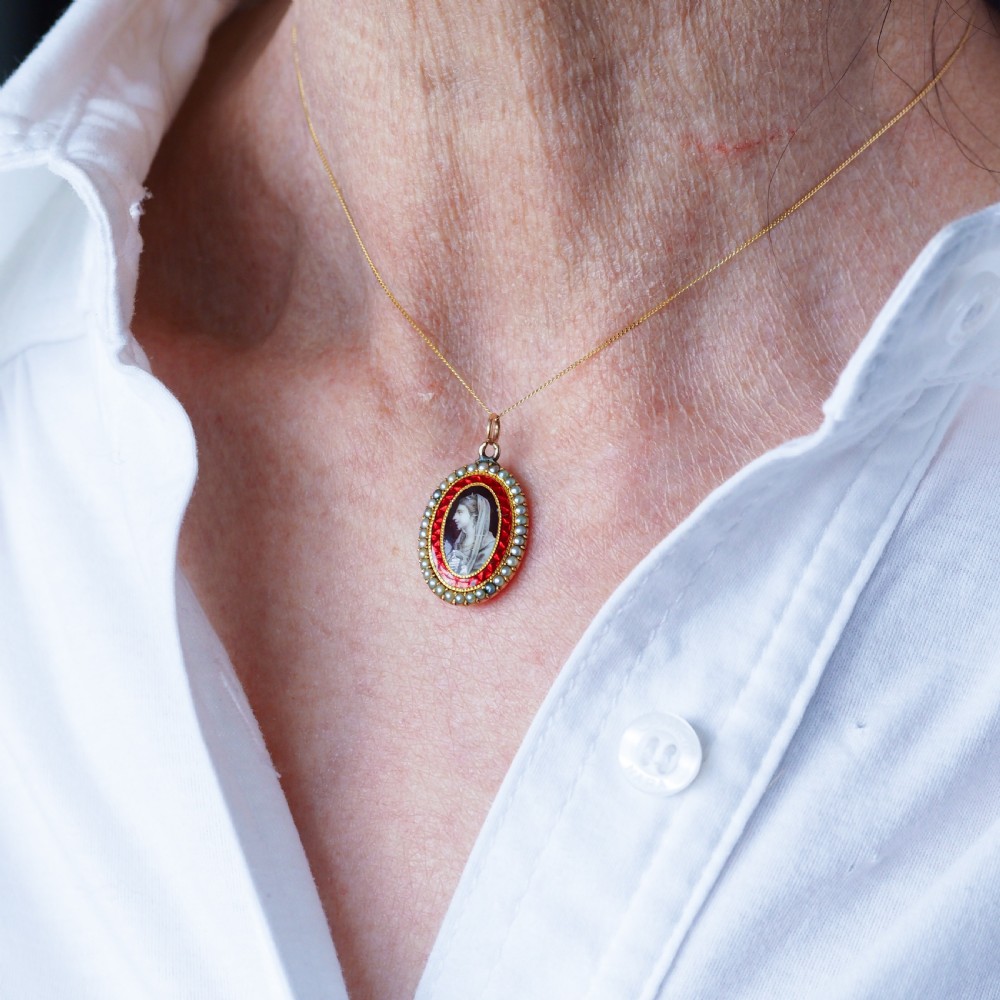 An oval Georgian gold pendant featuring a sepia miniature profile portrait surrounded by a red enamel border and a frame of seed pearls on a fine gold chain. View XII