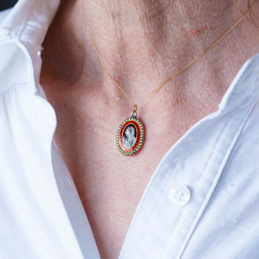An oval Georgian gold pendant featuring a sepia miniature profile portrait surrounded by a red enamel border and a frame of seed pearls on a fine gold chain. View XIII