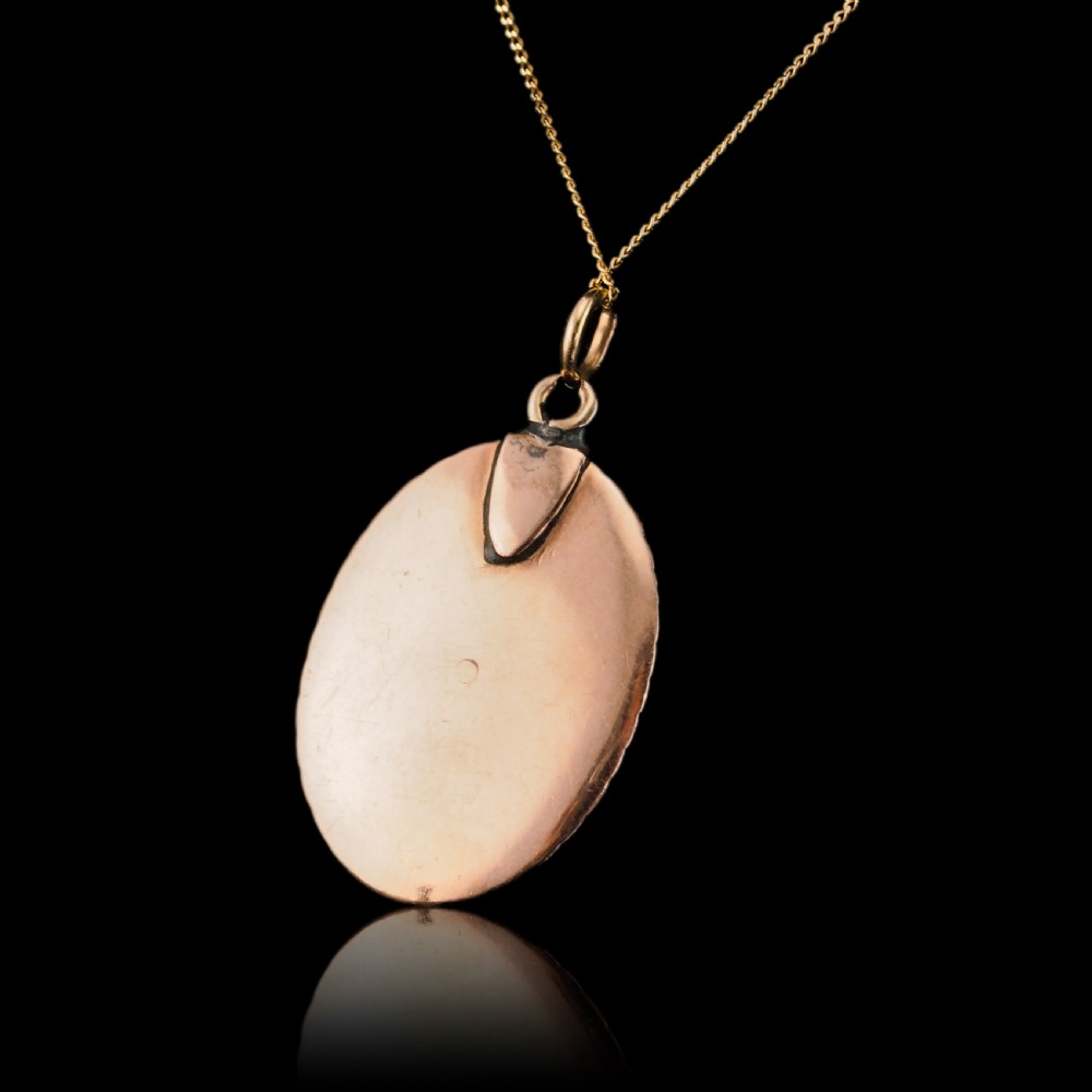 An oval Georgian gold pendant featuring a sepia miniature profile portrait surrounded by a red enamel border and a frame of seed pearls on a fine gold chain. View XV