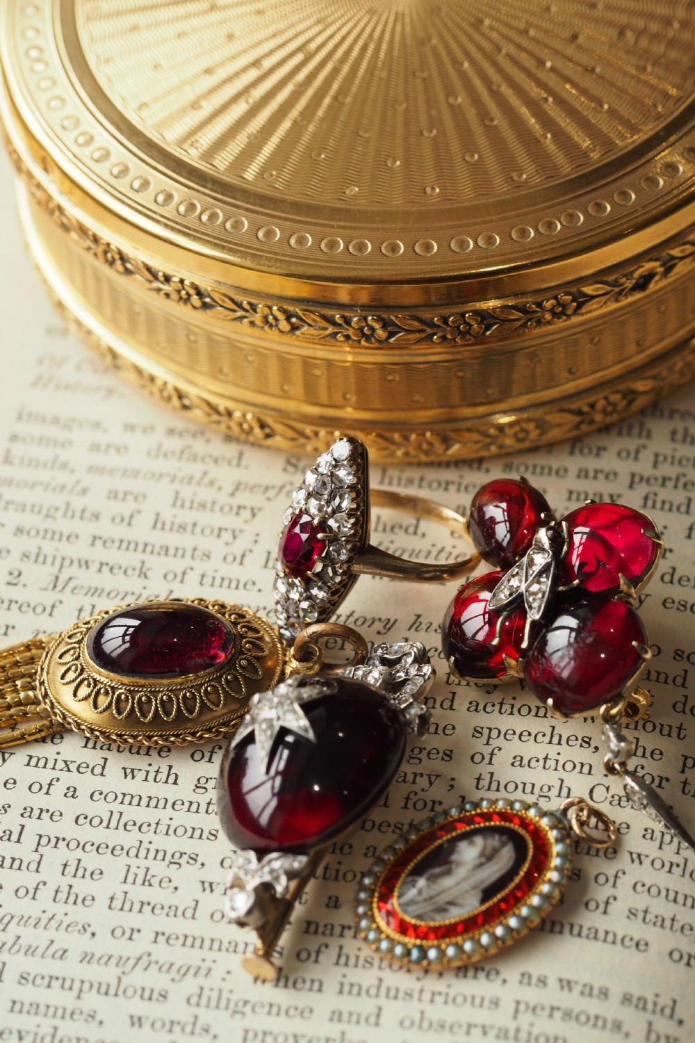 An oval Georgian gold pendant featuring a sepia miniature profile portrait surrounded by a red enamel border and a frame of seed pearls on a fine gold chain. View XVI