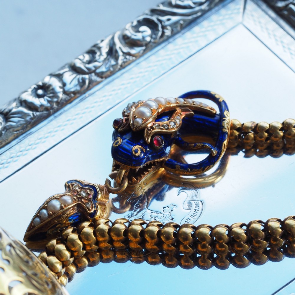 An antique Victorian 18-carat gold snake necklace featuring a flexible chain and a blue enamel serpent head decorated with seed pearls and diamonds. View XVIII