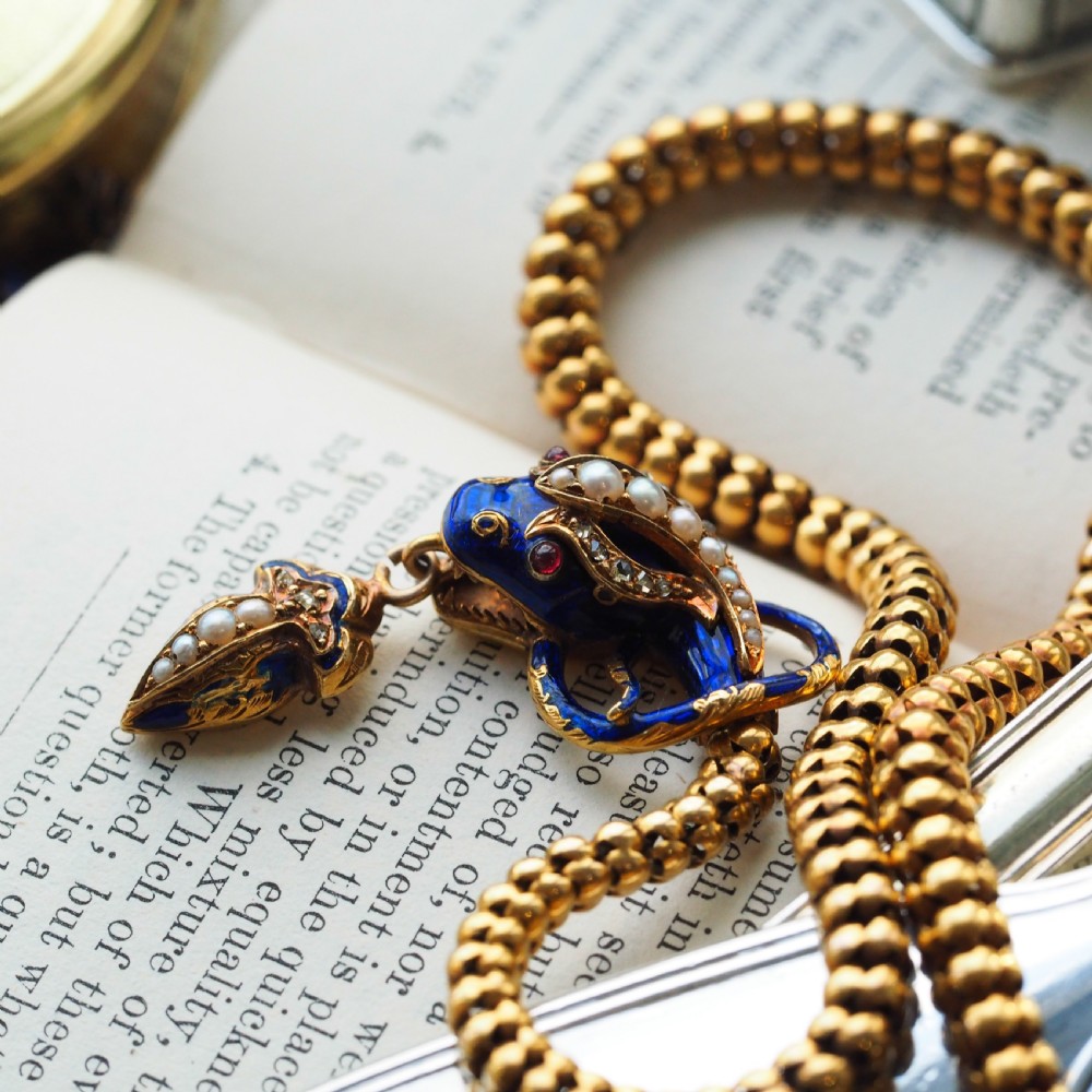 An antique Victorian 18-carat gold snake necklace featuring a flexible chain and a blue enamel serpent head decorated with seed pearls and diamonds. View IV