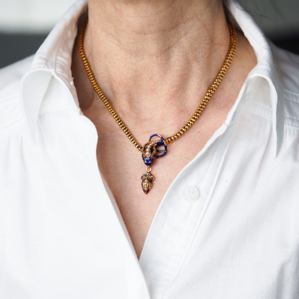 A Victorian 18-carat gold woven chain necklace featuring a blue enamel snake head set with seed pearls, small diamonds, and ruby eyes. View IX