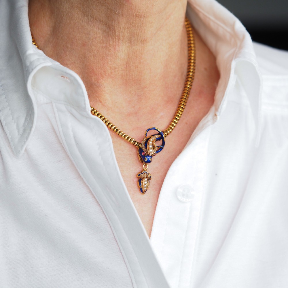 A Victorian 18-carat gold woven chain necklace featuring a blue enamel snake head set with seed pearls, small diamonds, and ruby eyes. View X
