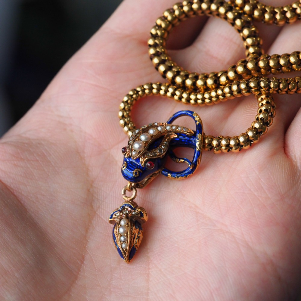 A Victorian 18-carat gold woven chain necklace featuring a blue enamel snake head set with seed pearls, small diamonds, and ruby eyes. View XIX