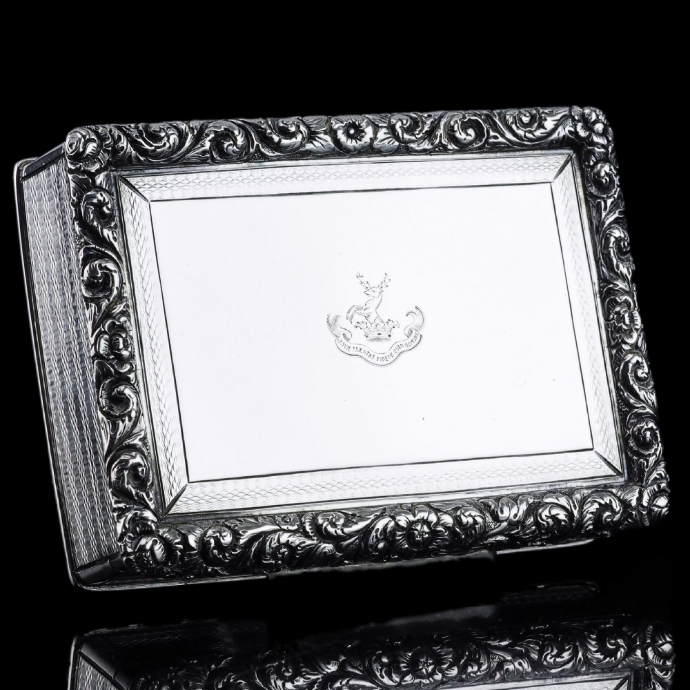 A rectangular sterling silver Georgian snuff box featuring a chased floral border, engine-turned detailing, and a central engraved crest. View V