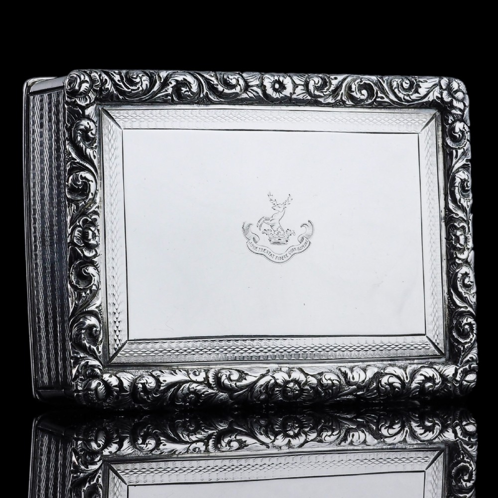 A rectangular sterling silver Georgian snuff box featuring a chased floral border, engine-turned detailing, and a central engraved crest. View III