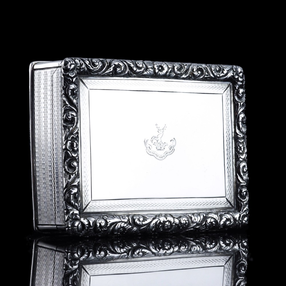A rectangular sterling silver Georgian snuff box featuring a chased floral border, engine-turned detailing, and a central engraved crest. View VI