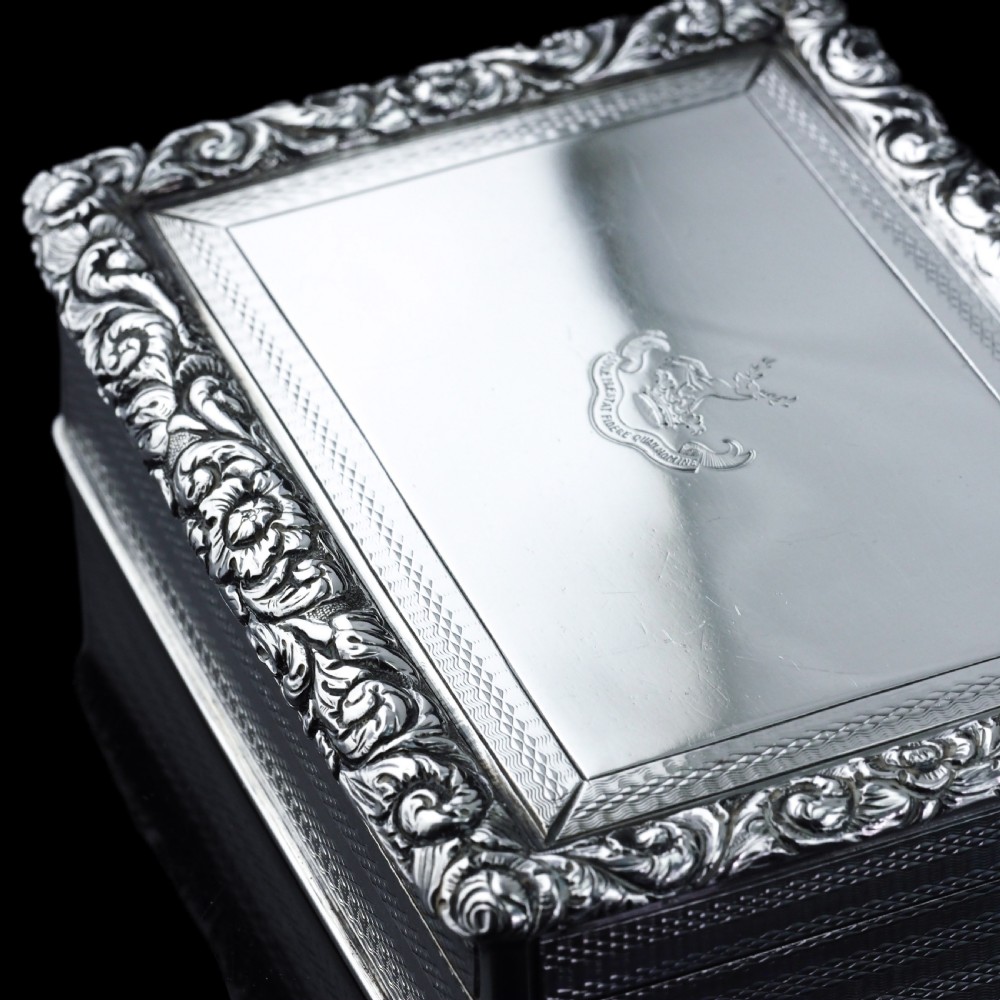 A rectangular sterling silver Georgian snuff box featuring a chased floral border, engine-turned detailing, and a central engraved crest. View XVII