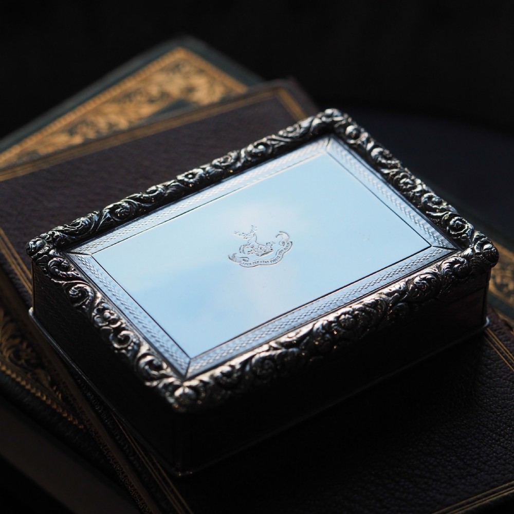 A rectangular sterling silver Georgian snuff box featuring a chased floral border, engine-turned detailing, and a central engraved crest. View XIX