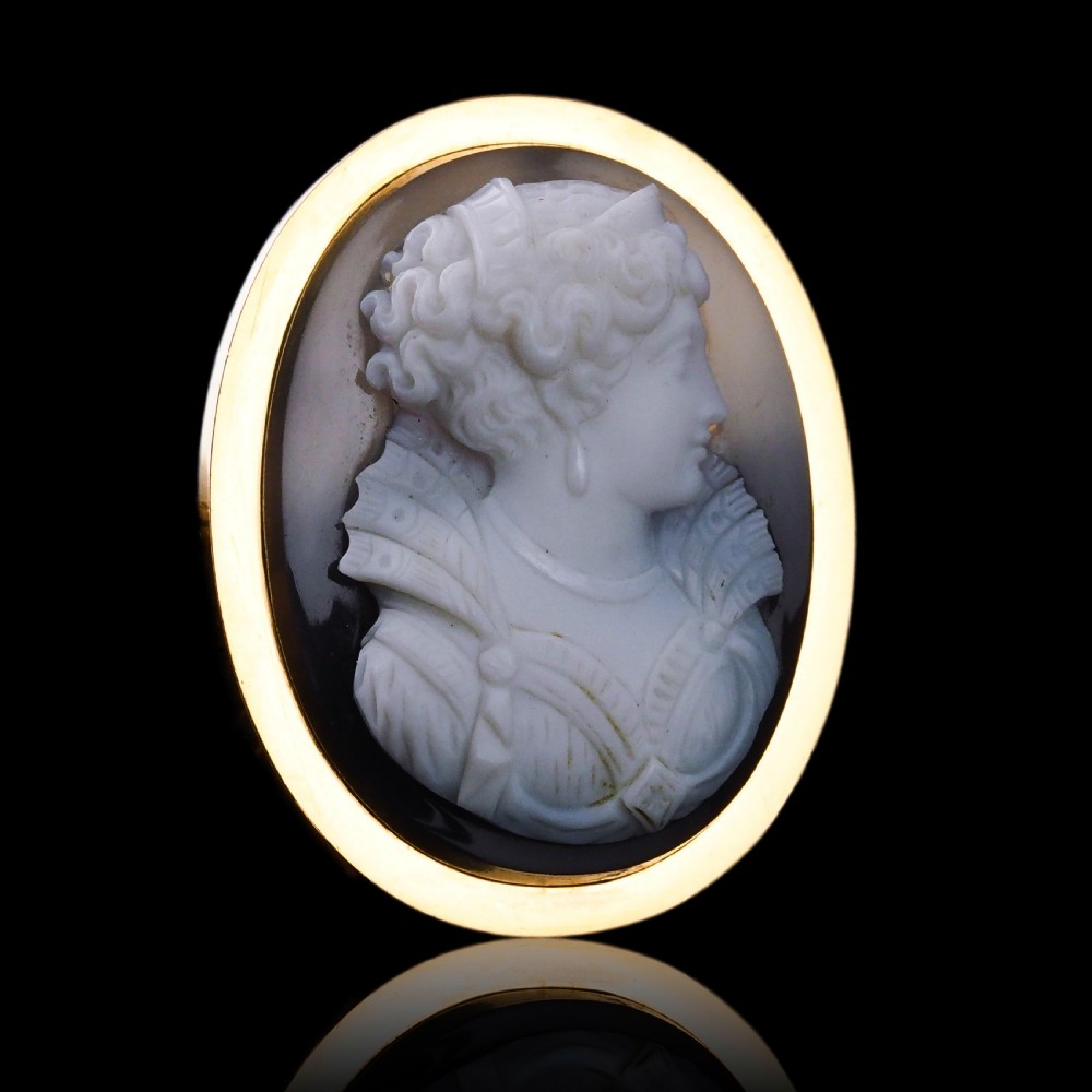 An oval Victorian hardstone agate cameo featuring a white relief carved portrait of a woman against a dark background, set in a plain 18ct gold bezel frame. View II