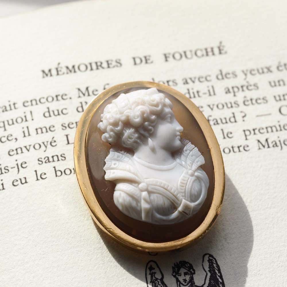An oval Victorian hardstone agate cameo featuring a white relief carved portrait of a woman against a dark background, set in a plain 18ct gold bezel frame. View IV