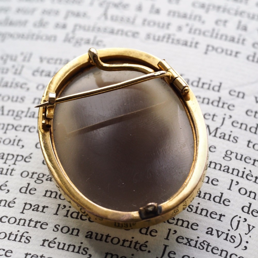 An oval Victorian hardstone agate cameo featuring a white relief carved portrait of a woman against a dark background, set in a plain 18ct gold bezel frame. View VIII