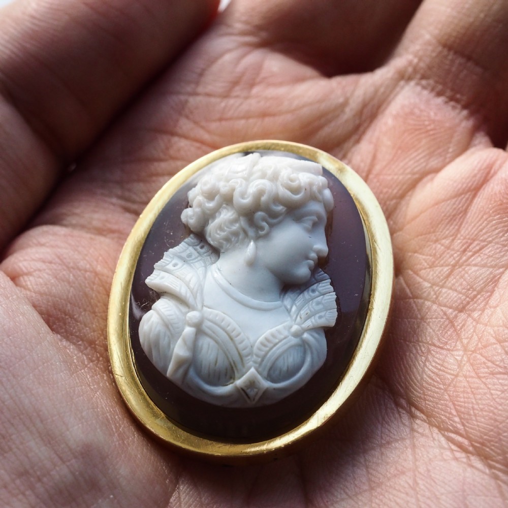 An oval Victorian hardstone agate cameo featuring a white relief carved portrait of a woman against a dark background, set in a plain 18ct gold bezel frame. View XIV
