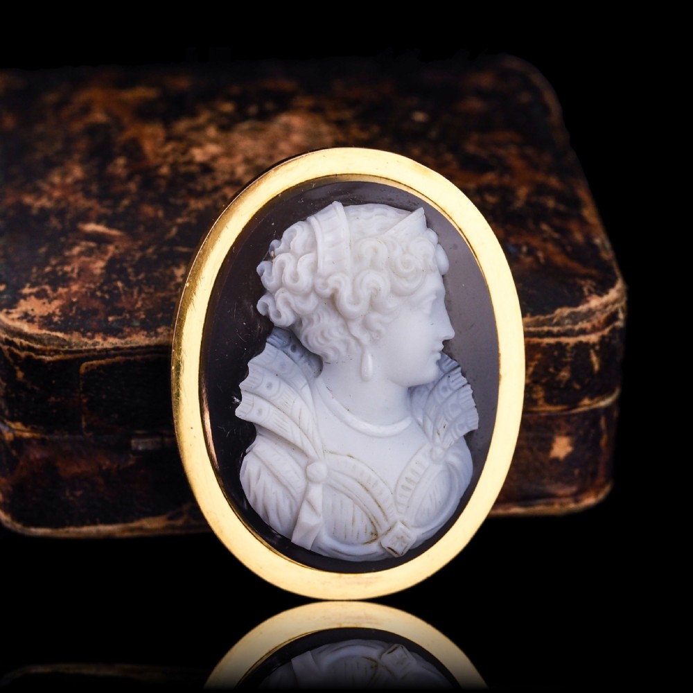An oval Victorian hardstone agate cameo featuring a white relief carved portrait of a woman against a dark background, set in a plain 18ct gold bezel frame. View XXI