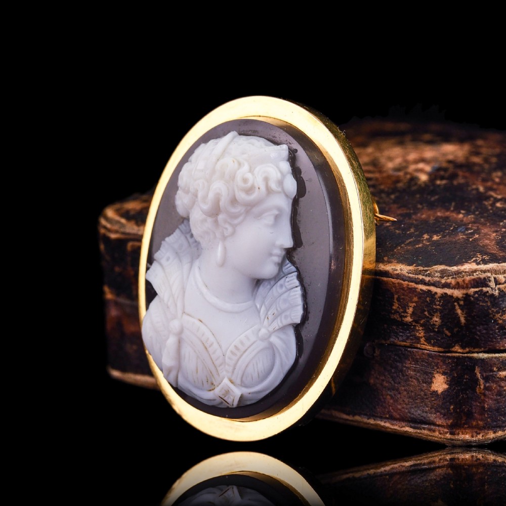 An oval Victorian hardstone agate cameo featuring a white relief carved portrait of a woman against a dark background, set in a plain 18ct gold bezel frame. View XXII