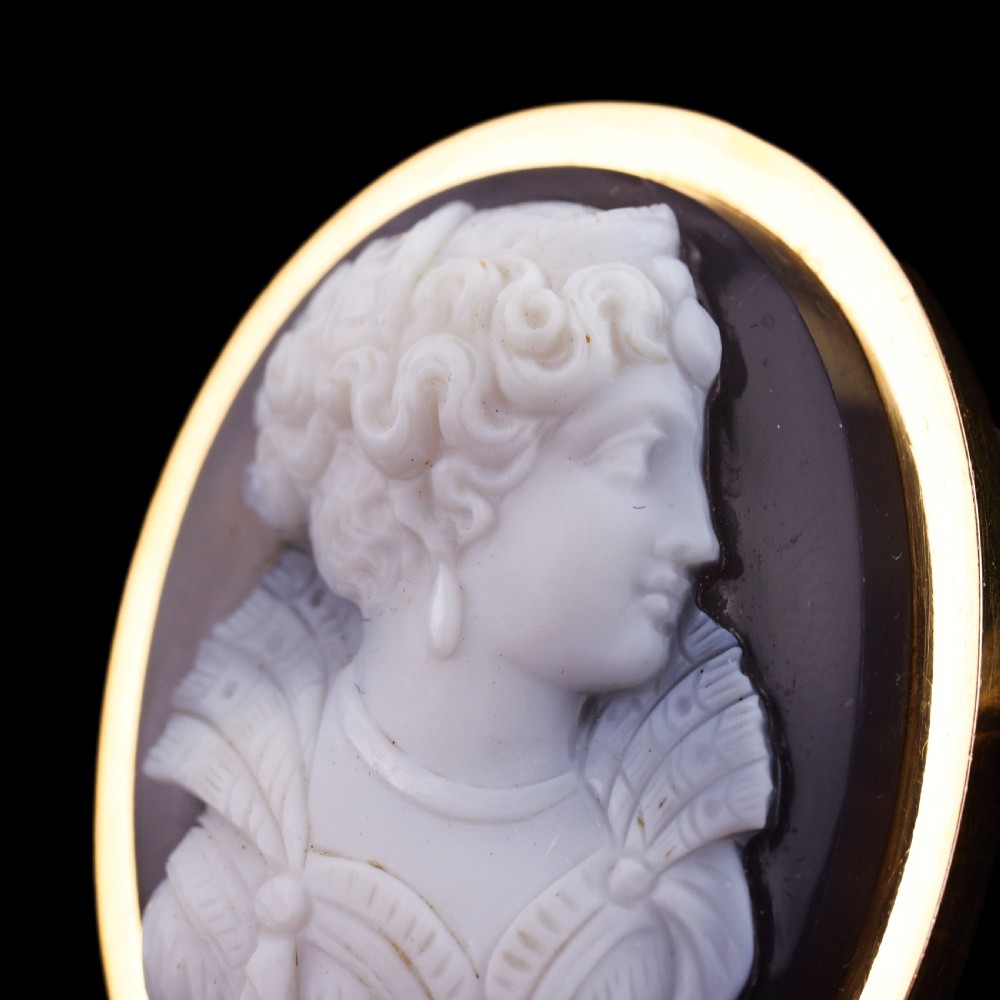 An oval Victorian hardstone agate cameo featuring a white relief carved portrait of a woman against a dark background, set in a plain 18ct gold bezel frame. View XXIII