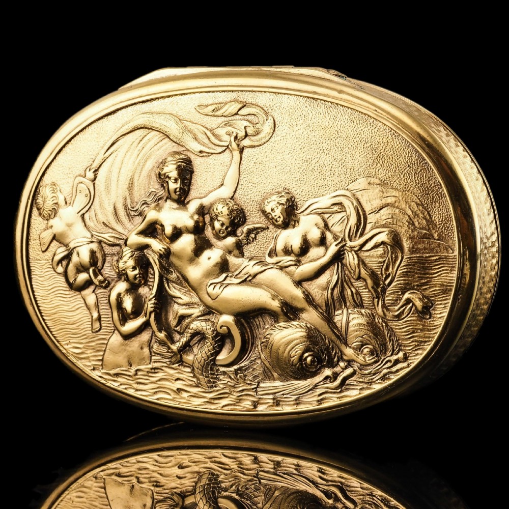 An oval Georgian silver-gilt snuff box featuring a detailed relief depicting Venus surrounded by attendants and cherubs on a textured ground.