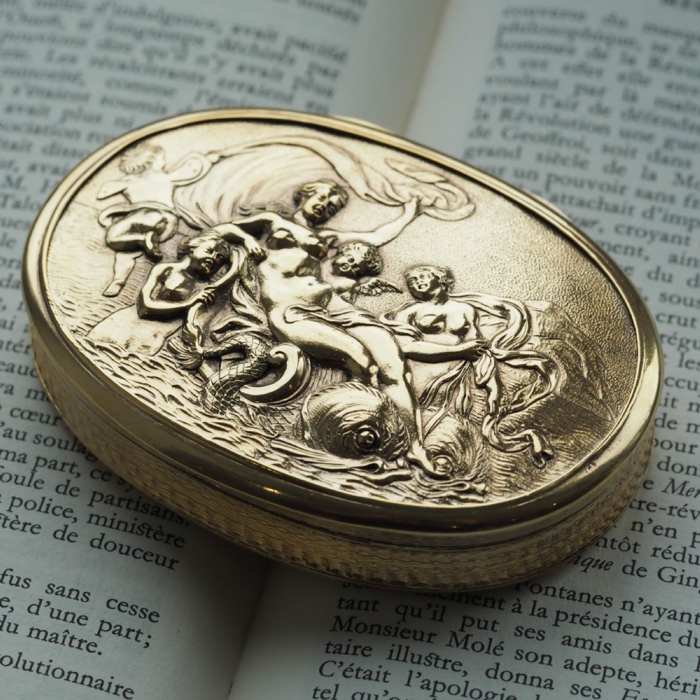 An oval Georgian silver-gilt snuff box featuring a detailed relief depicting Venus surrounded by attendants and cherubs on a textured ground. View X