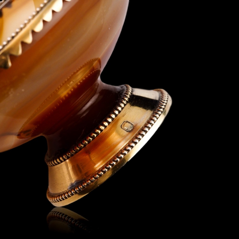 A 19th-century carved brown banded agate cup featuring a silver-gilt rim, pedestal base, and an ornate scroll handle. View IX