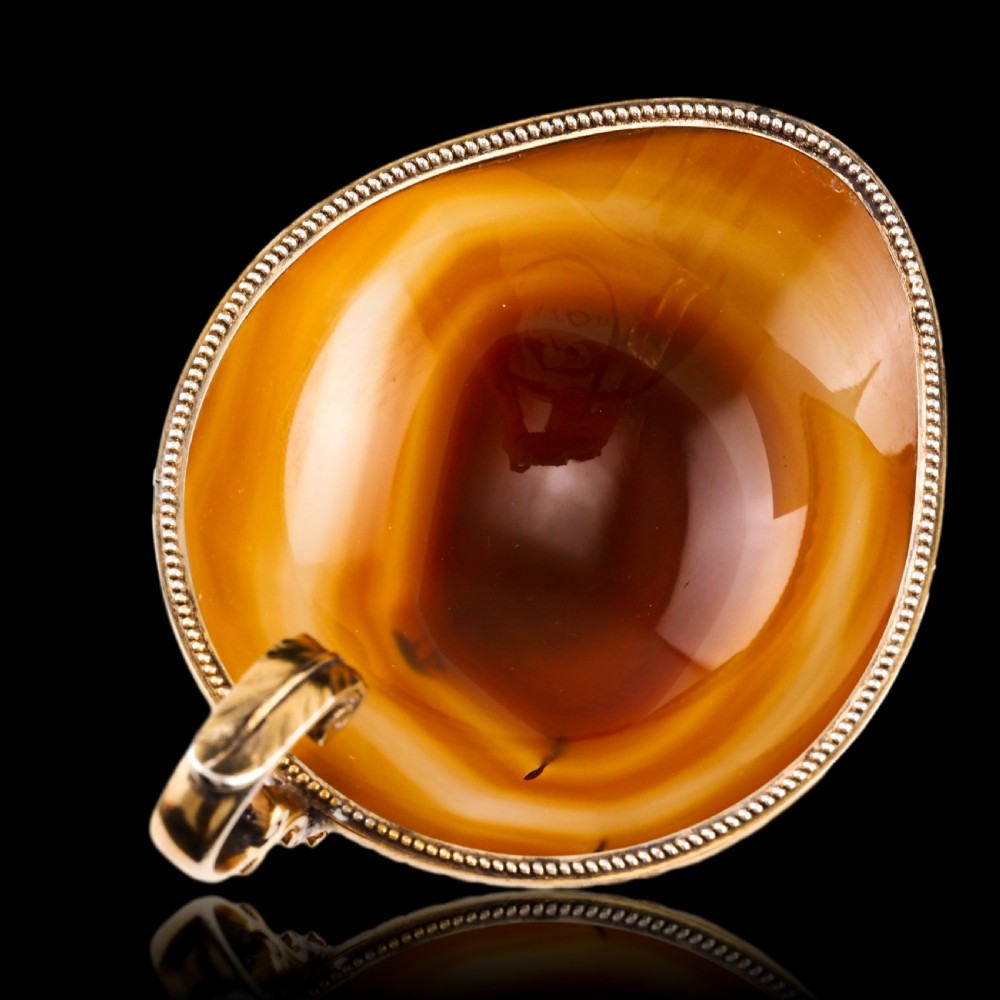 A 19th-century carved brown banded agate cup featuring a silver-gilt rim, pedestal base, and an ornate scroll handle. View XI