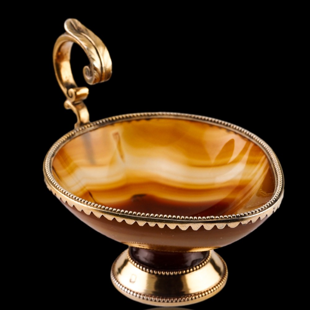 A 19th-century carved brown banded agate cup featuring a silver-gilt rim, pedestal base, and an ornate scroll handle. View XVII