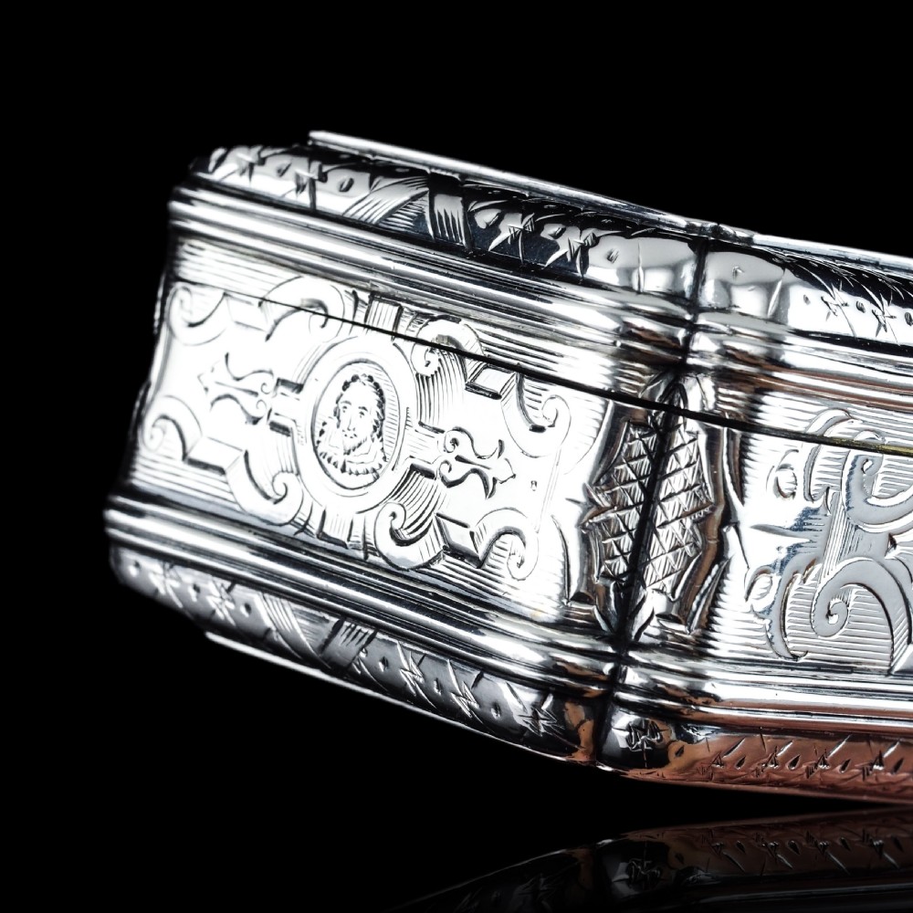 A Victorian sterling silver table snuff box with shaped cartouche outlines, foliage engraving, and an architectural scene. View III
