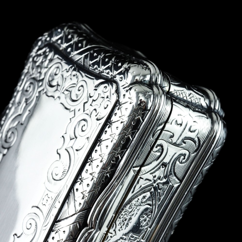 A Victorian sterling silver table snuff box with shaped cartouche outlines, foliage engraving, and an architectural scene. View IV