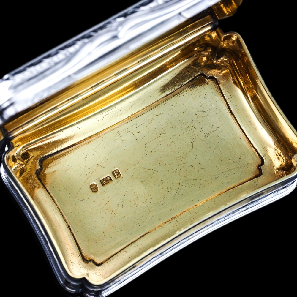 A Victorian sterling silver table snuff box with shaped cartouche outlines, foliage engraving, and an architectural scene. View VI