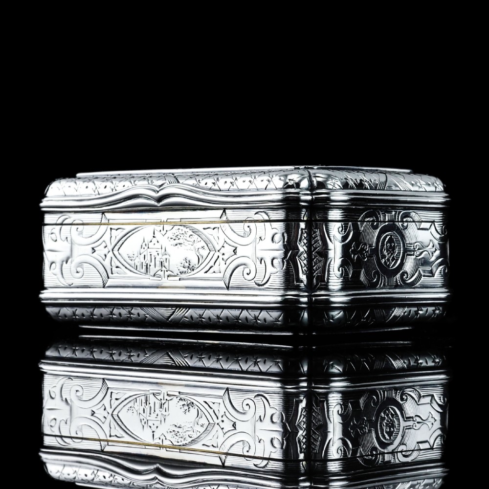 A Victorian sterling silver table snuff box with shaped cartouche outlines, foliage engraving, and an architectural scene. View X