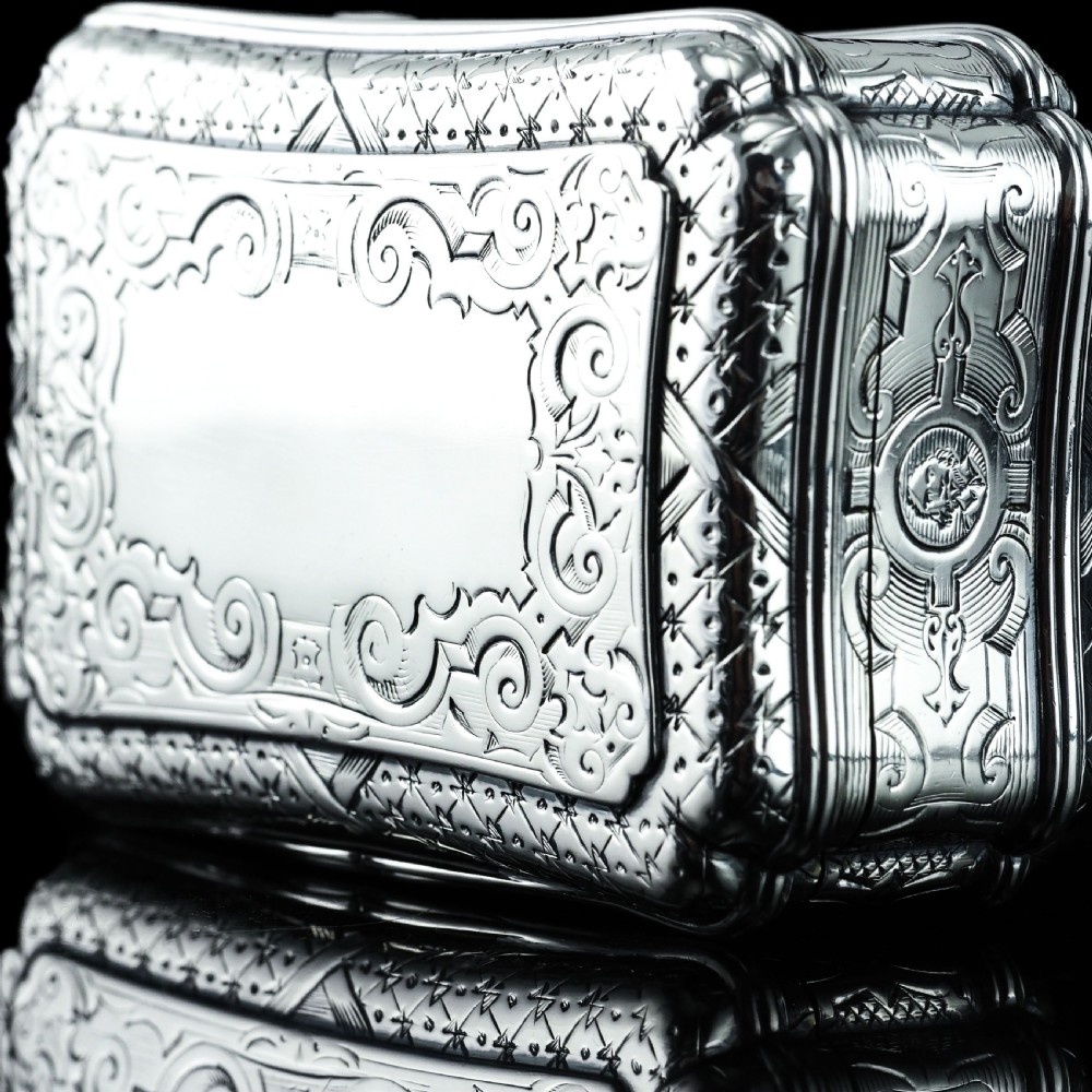 A Victorian sterling silver table snuff box with shaped cartouche outlines, foliage engraving, and an architectural scene. View XII