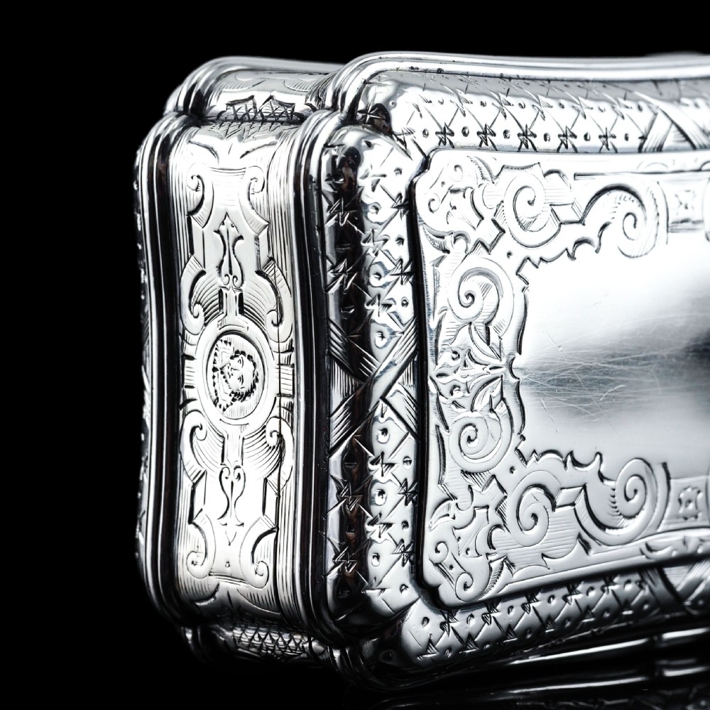 A Victorian sterling silver table snuff box with shaped cartouche outlines, foliage engraving, and an architectural scene. View XIII