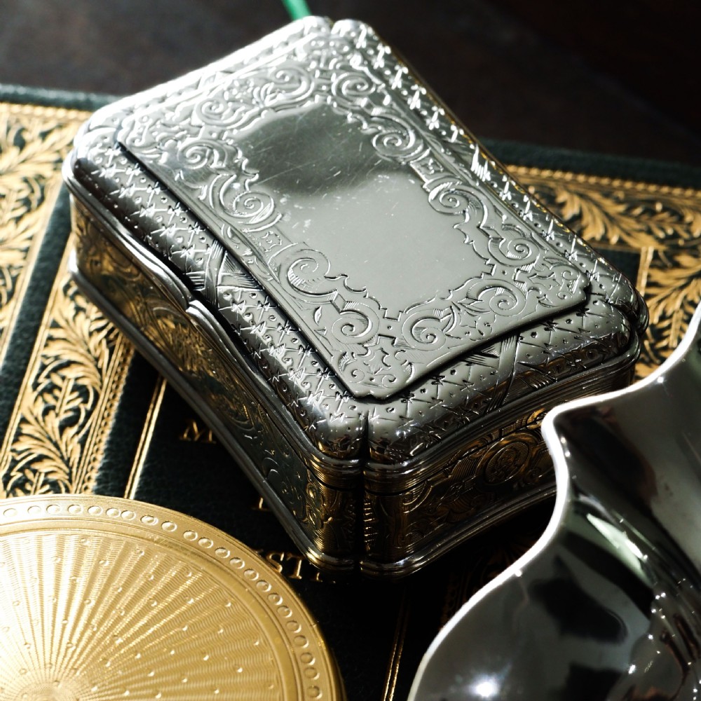 A Victorian sterling silver table snuff box with shaped cartouche outlines, foliage engraving, and an architectural scene. View XXIII