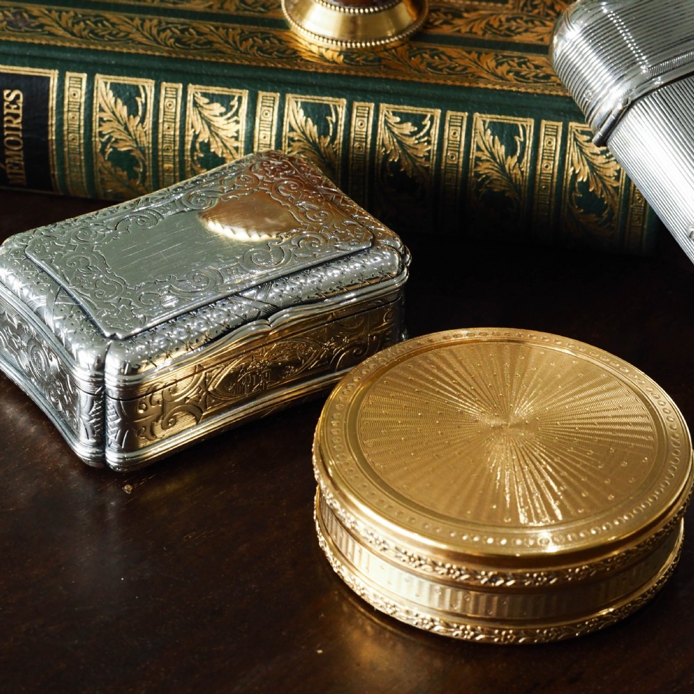 A Victorian sterling silver table snuff box with shaped cartouche outlines, foliage engraving, and an architectural scene. View XXVI