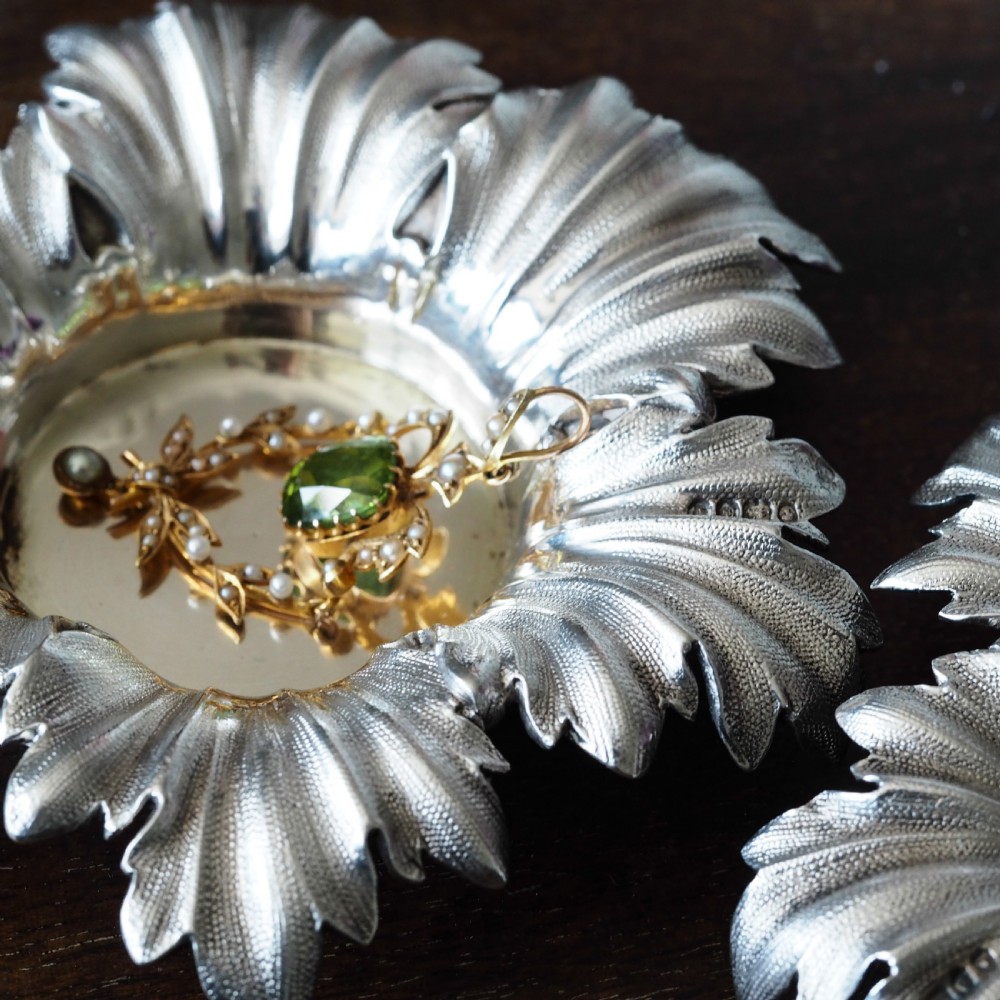 Pair of Victorian sterling silver open salt dishes featuring detailed chased leaf motifs radiating around a central polished circular well. View II