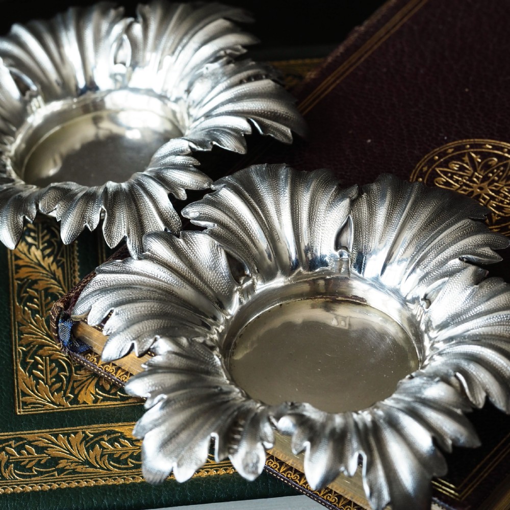Pair of Victorian sterling silver open salt dishes featuring detailed chased leaf motifs radiating around a central polished circular well. View VI