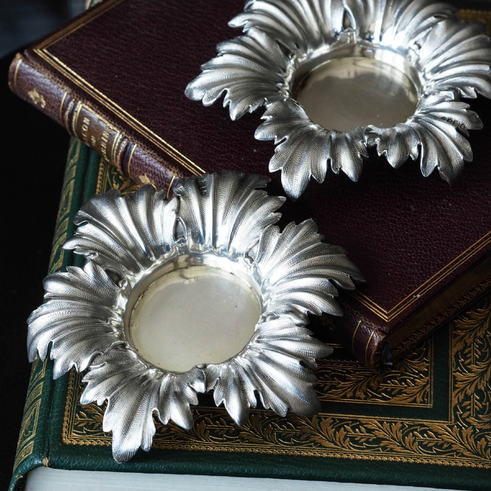 Pair of Victorian sterling silver open salt dishes featuring detailed chased leaf motifs radiating around a central polished circular well. View VII