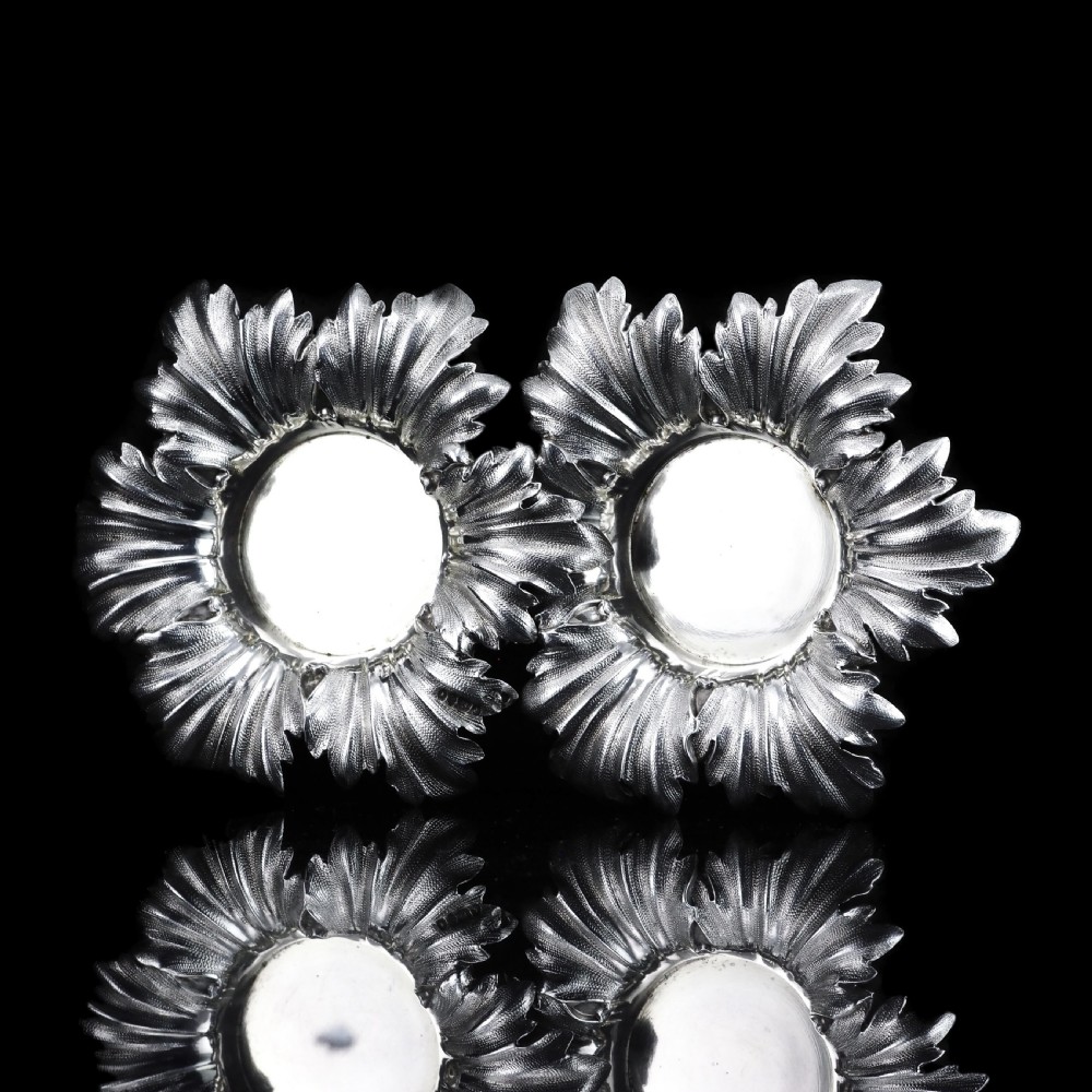 Pair of Victorian sterling silver open salt dishes featuring detailed chased leaf motifs radiating around a central polished circular well. View X