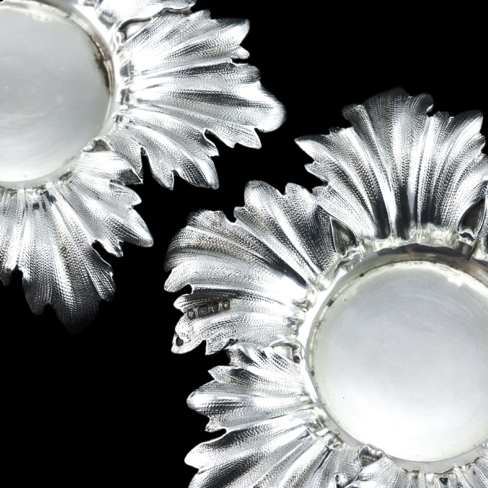 Pair of Victorian sterling silver open salt dishes featuring detailed chased leaf motifs radiating around a central polished circular well. View XV