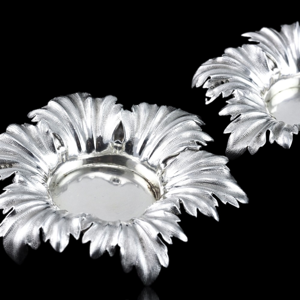 Pair of Victorian sterling silver open salt dishes featuring detailed chased leaf motifs radiating around a central polished circular well. View XVI