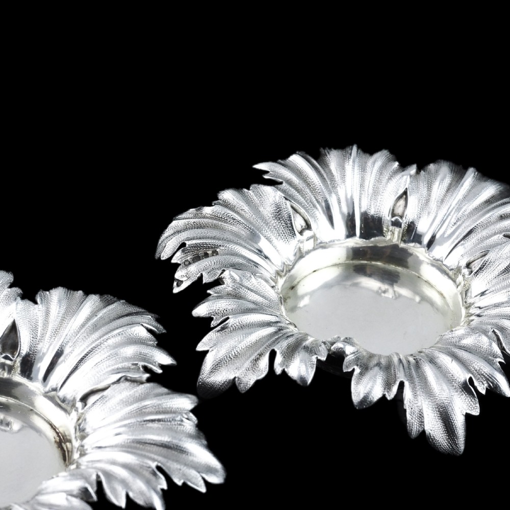 Pair of Victorian sterling silver open salt dishes featuring detailed chased leaf motifs radiating around a central polished circular well. View XVII