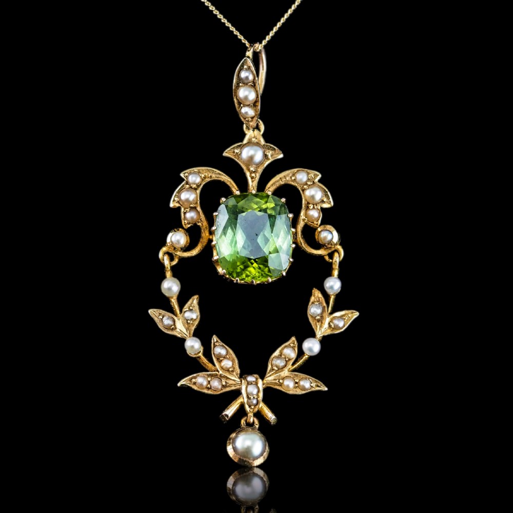 A late Victorian 14-carat yellow gold openwork pendant featuring a cushion-cut green peridot encircled by seed pearl foliate scrolls and a dangling pearl drop. View II