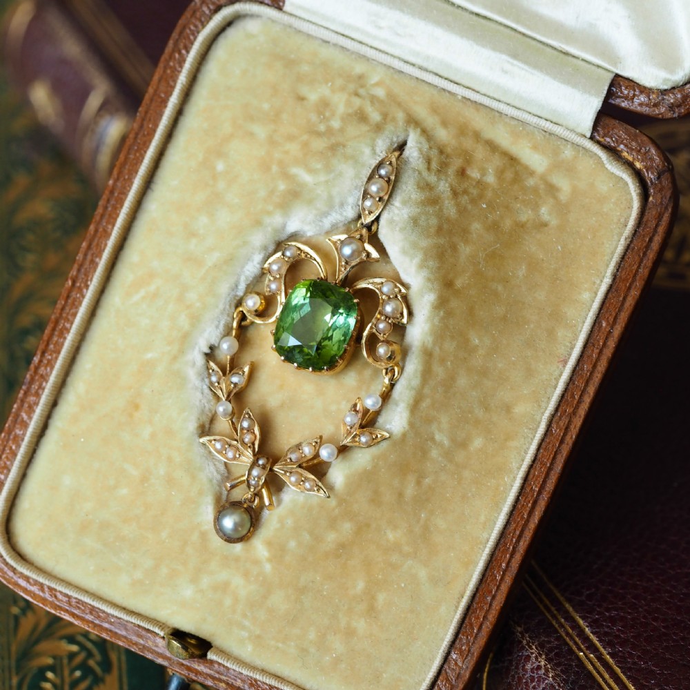 A late Victorian 14-carat yellow gold openwork pendant featuring a cushion-cut green peridot encircled by seed pearl foliate scrolls and a dangling pearl drop. View IV