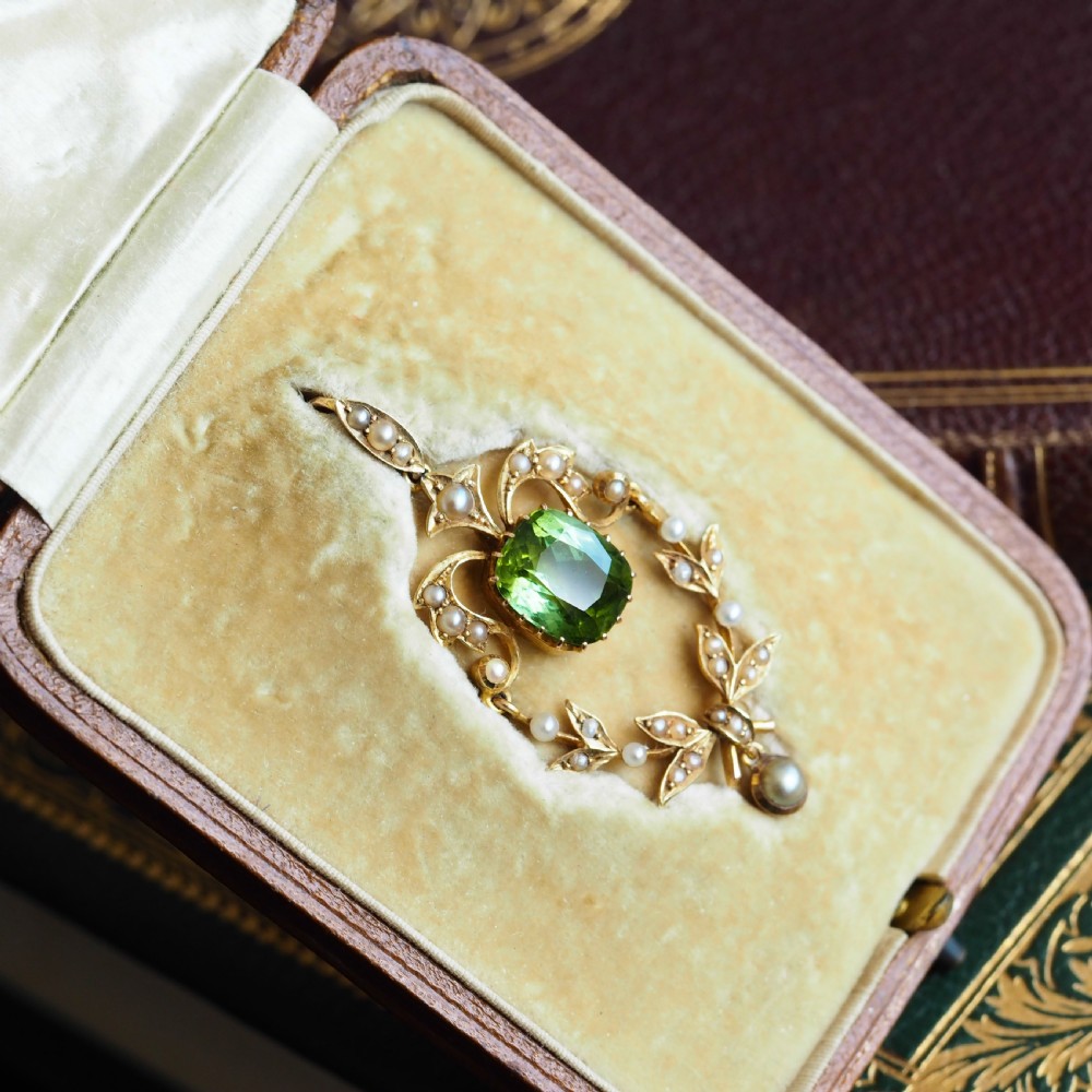 A late Victorian 14-carat yellow gold openwork pendant featuring a cushion-cut green peridot encircled by seed pearl foliate scrolls and a dangling pearl drop. View VII