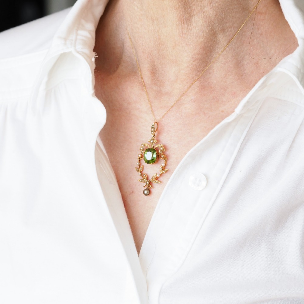 A late Victorian 14-carat yellow gold openwork pendant featuring a cushion-cut green peridot encircled by seed pearl foliate scrolls and a dangling pearl drop. View VIII